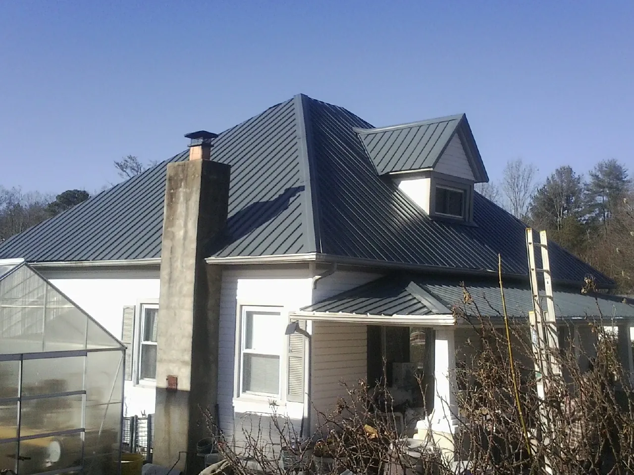 Dark blue standing seam metal roof on a white farmhouse with dormer — Slate & Tile Roof Repair by Roofing Brothers in Highwood