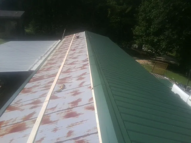 Old rusted panels beside newly installed green metal roofing — Wind Damage Roof Repair by Roofing Brothers in Highwood