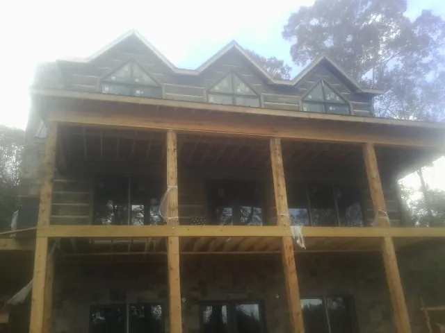 Dormers and porch framing on a large log home under construction — Roof Coating work by our crew in Highwood