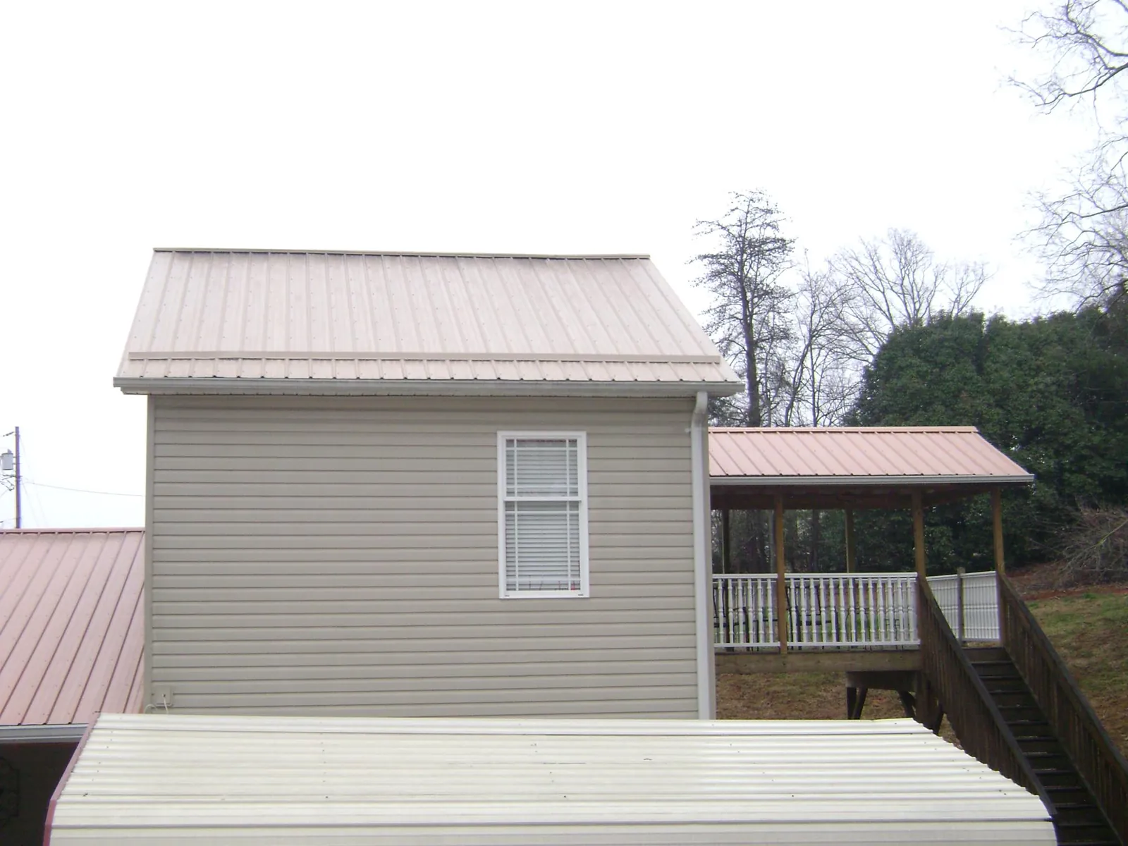 Tan metal roofs on a two story addition and attached porch, from a Roof Replacement job in Highwood