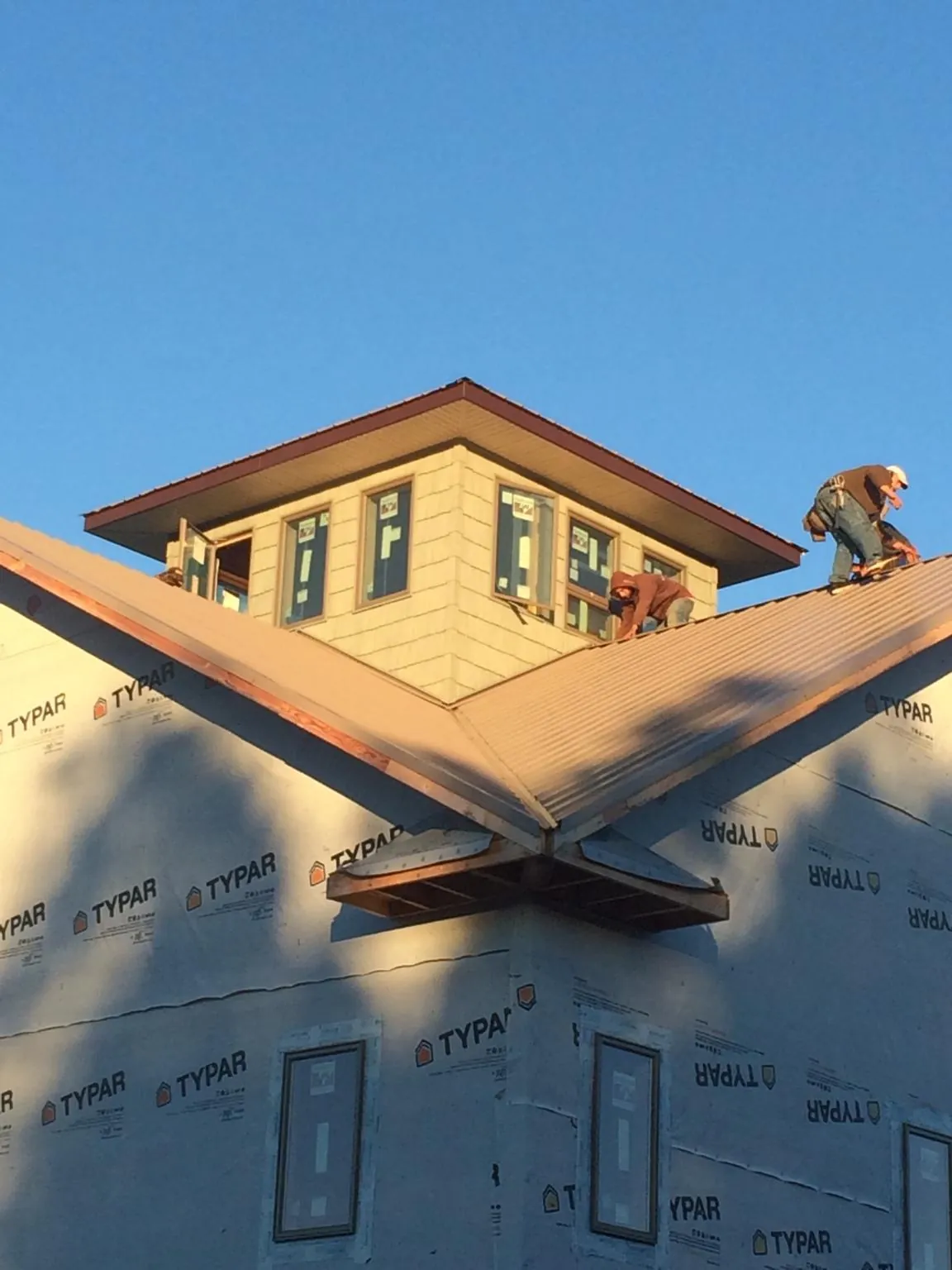 Roofers working around a rooftop cupola on a new metal roof at sunset — Roof Waterproofing in Highwood by Roofing Brothers